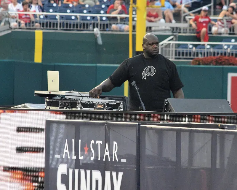 Shaquille O'Neal performing as DJ Diesel behind a DJ booth at the 2018 MLB All-Star Legends & Celebrity Softball Game at Nationals Park, Washington, D.C.